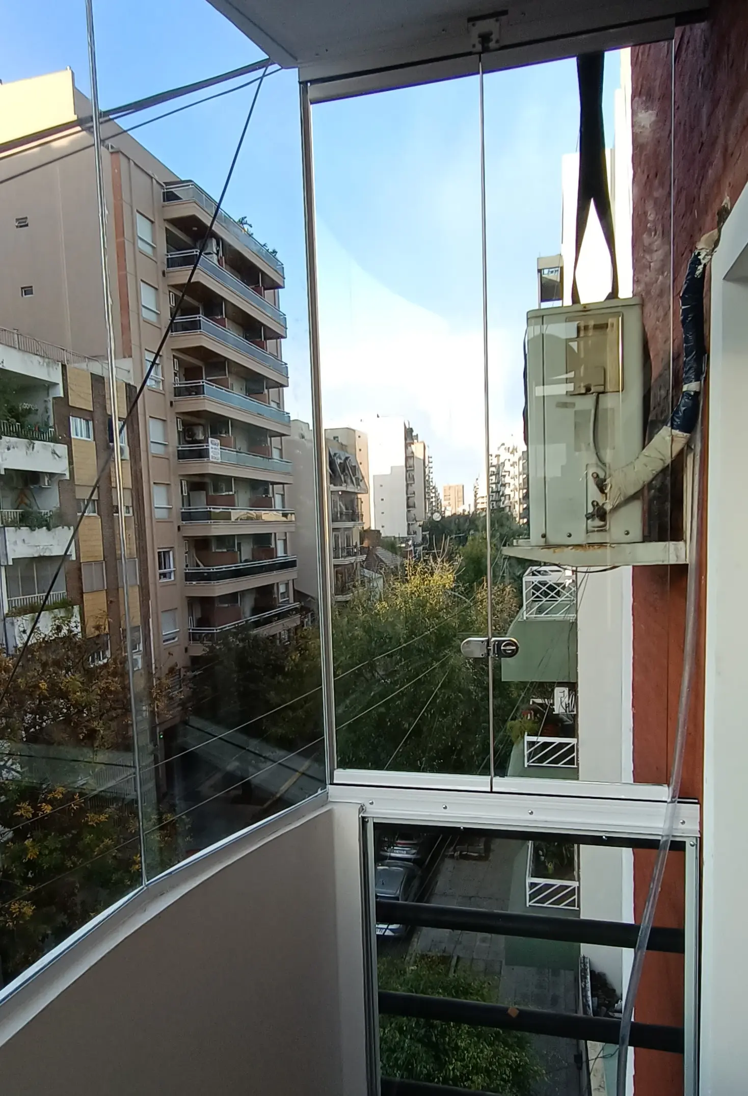 Terraza escalonada con barandas de vidrio y canteros con plantas