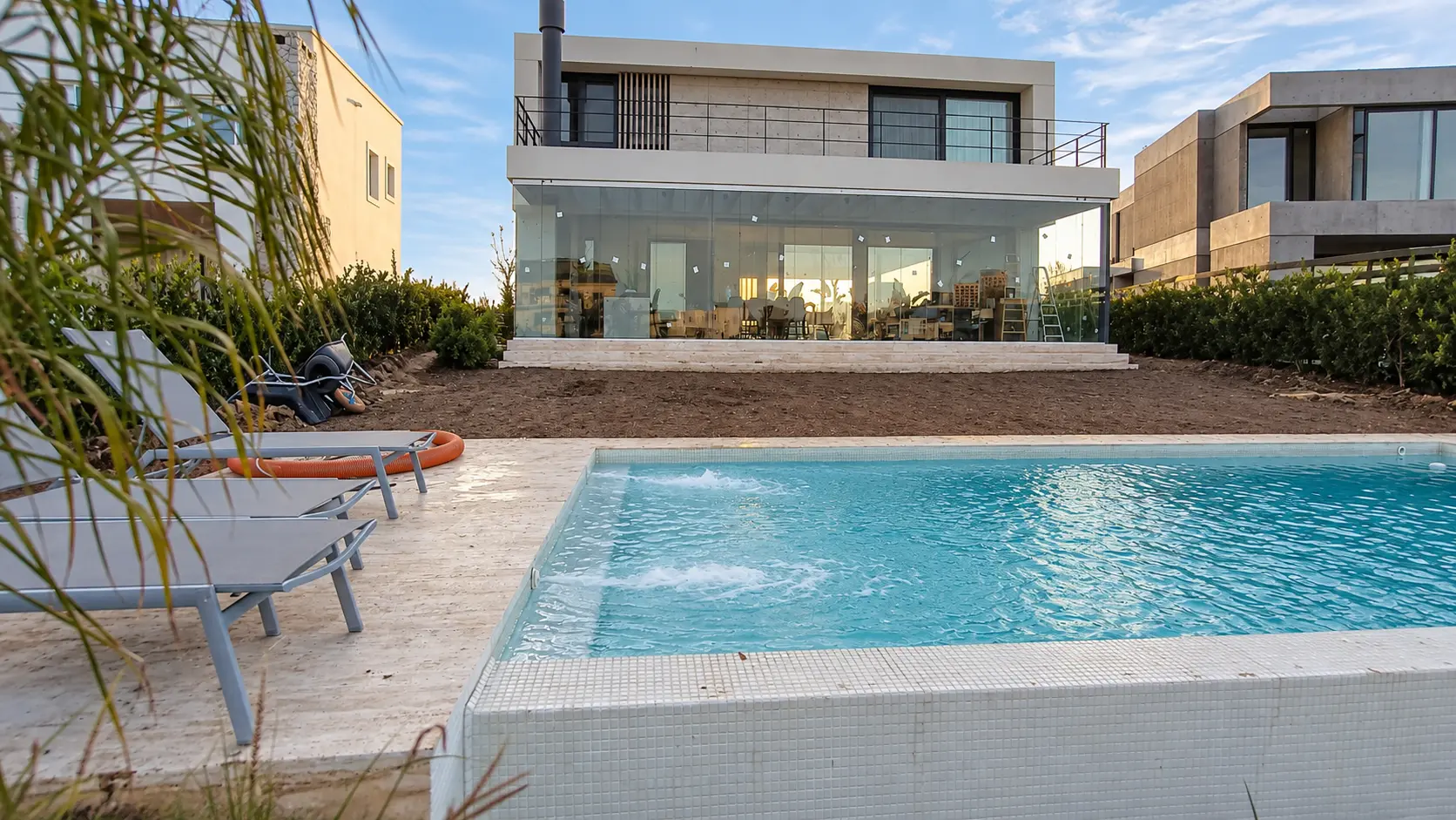 Casa con cerramiento de vidrio en planta baja y baranda de vidrio en el balcón superior